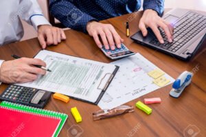 persona llenando formulario con factura y computadora